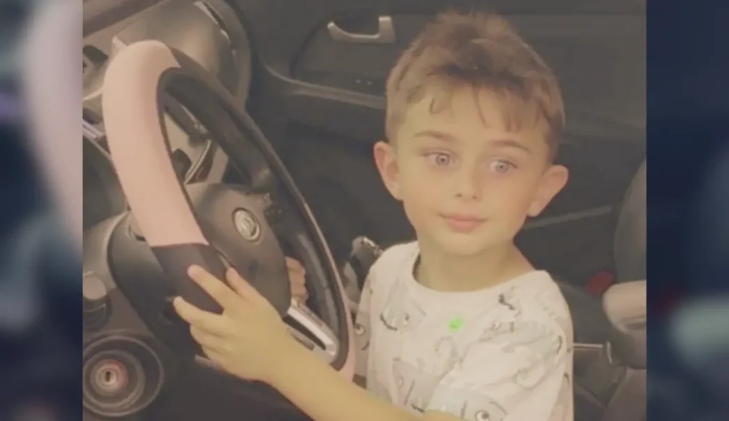 El niño Zaahir Jan Feizi sentado al volante de un vehículo sujetando el volante.