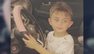 El niño Zaahir Jan Feizi sentado al volante de un vehículo sujetando el volante.