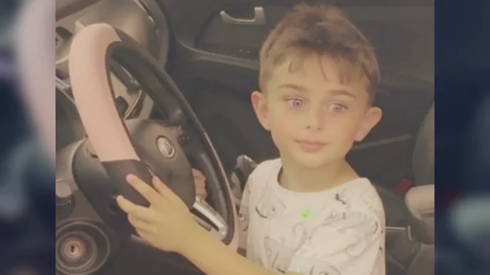 El niño Zaahir Jan Feizi sentado al volante de un vehículo sujetando el volante.