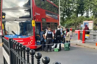 Agentes de policía y servicios de emergencia atendiendo a un peatón en el suelo junto a un autobús rojo de dos pisos acordonado en Walthamstow.