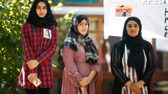 Tres mujeres afganas vestidas con hiyab y túnicas tradicionales posan de pie en un espacio público.