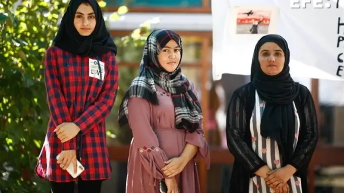 Tres mujeres afganas vestidas con hiyab y túnicas tradicionales posan de pie en un espacio público.