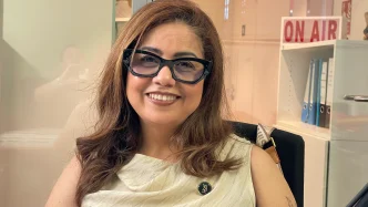 Diana Paola Rincón Gómez, fundadora de Hoff, sonriente con gafas oscuras de pasta y pin corporativo en una oficina.