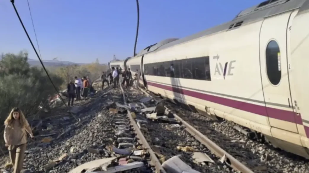 Tren AVE de Renfe descarrilado en la vía con escombros esparcidos y pasajeros evacuados en la zona del accidente ferroviario en Toledo.