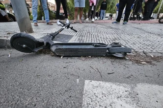Patinete o vehículo ligero tumbado en la acera tras un accidente de tráfico con testigos alrededor.