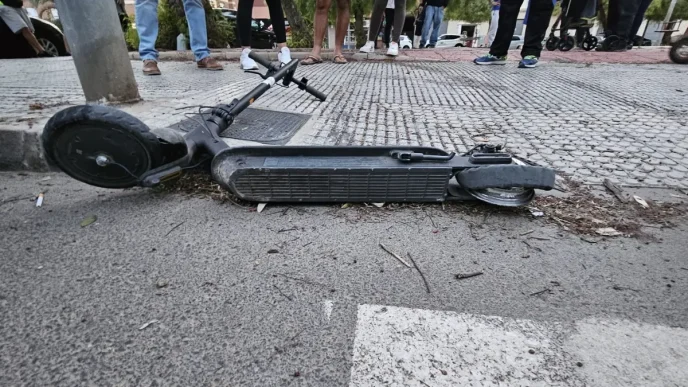 Patinete o vehículo ligero tumbado en la acera tras un accidente de tráfico con testigos alrededor.