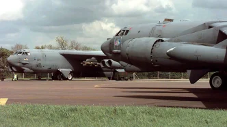 Dos bombarderos militares pesados estacionados en la plataforma de asfalto de una base aérea bajo un cielo nublado.