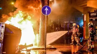 Contenedores incendiados y vehículos calcinados durante los disturbios nocturnos en el centro urbano.