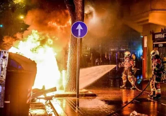 Contenedores incendiados y vehículos calcinados durante los disturbios nocturnos en el centro urbano.