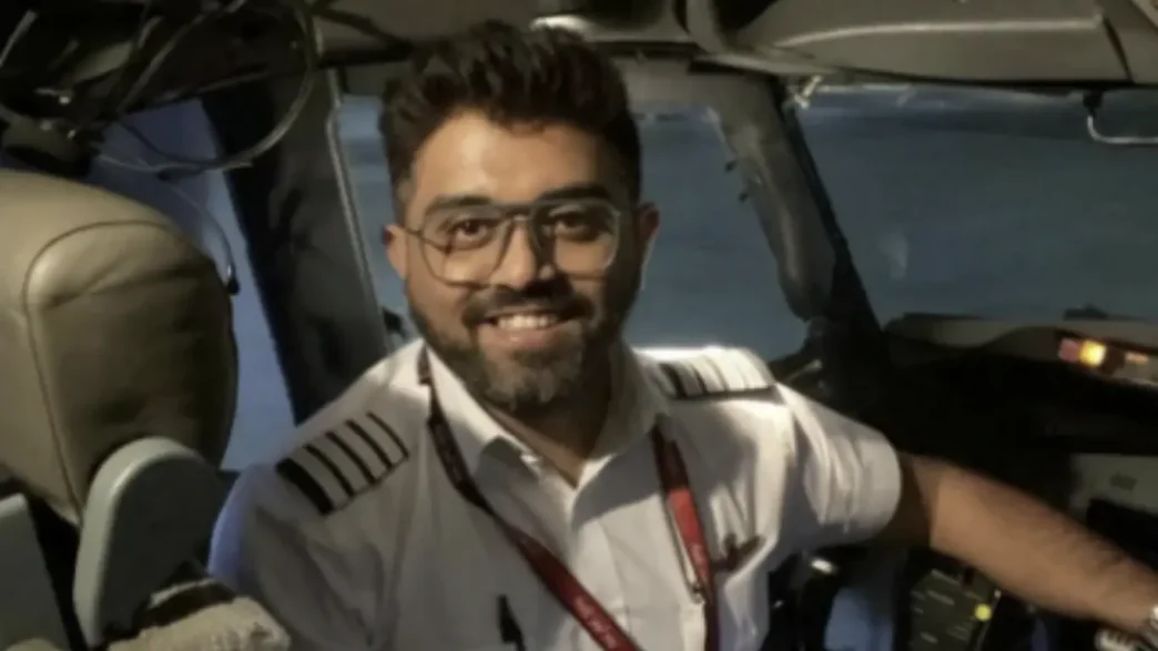 El capitán Smit Machchhar sonriendo dentro de la cabina de mando de un avión comercial.