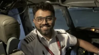 El capitán Smit Machchhar sonriendo dentro de la cabina de mando de un avión comercial.