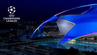 Logo de la UEFA Champions League junto a la estructura de un estadio iluminado de azul en la noche.