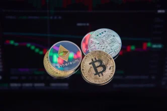 Monedas físicas de criptomonedas como Bitcoin y Ethereum sobre un fondo de gráficos bursátiles digitales.