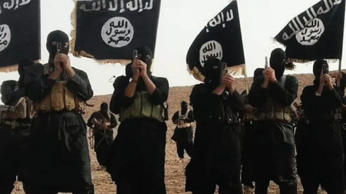 Combatientes del grupo terrorista ISIS encapuchados sosteniendo armas de fuego y banderas negras.