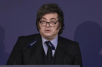El presidente de Argentina, Javier Milei, hablando desde un atril con gafas de pasta negra y traje oscuro.