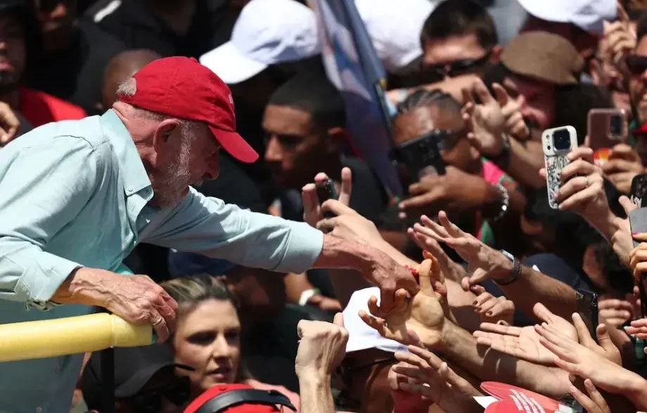 Luiz Inácio Lula da Silva con gorra roja estrechando la mano de sus seguidores en un acto multitudinario.