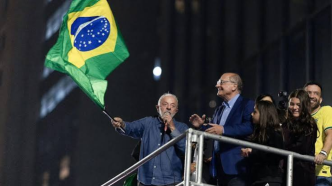 Luiz Inácio Lula da Silva sostiene una bandera de Brasil sobre una tarima rodeado de simpatizantes y aliados políticos