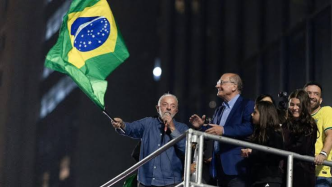 Luiz Inácio Lula da Silva sostiene una bandera de Brasil sobre una tarima rodeado de simpatizantes y aliados políticos