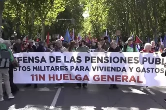 Manifestantes encabezan una marcha en Madrid sosteniendo una gran pancarta blanca por la defensa de las pensiones públicas.