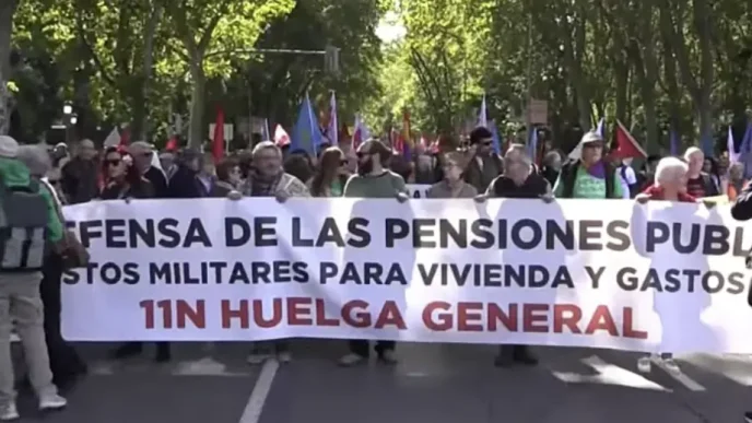 Manifestantes encabezan una marcha en Madrid sosteniendo una gran pancarta blanca por la defensa de las pensiones públicas.