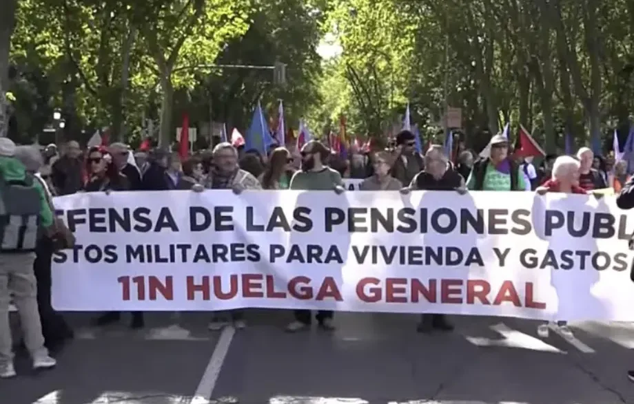 Manifestantes encabezan una marcha en Madrid sosteniendo una gran pancarta blanca por la defensa de las pensiones públicas.