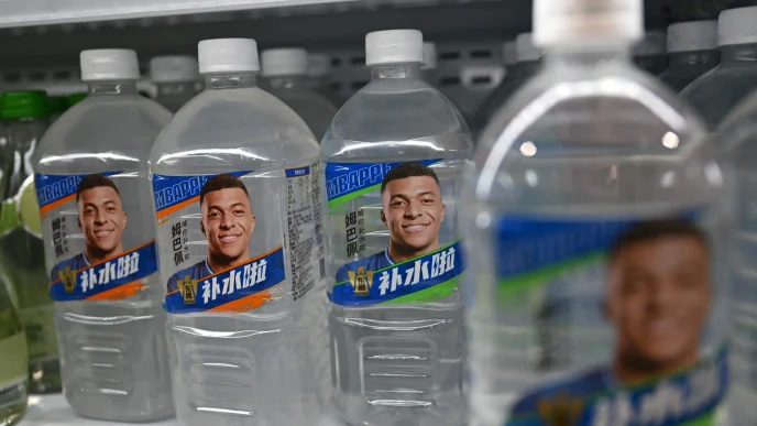 Botellas de agua en un estante de supermercado con la cara impres de Kylian Mbappé en la etiqueta.
