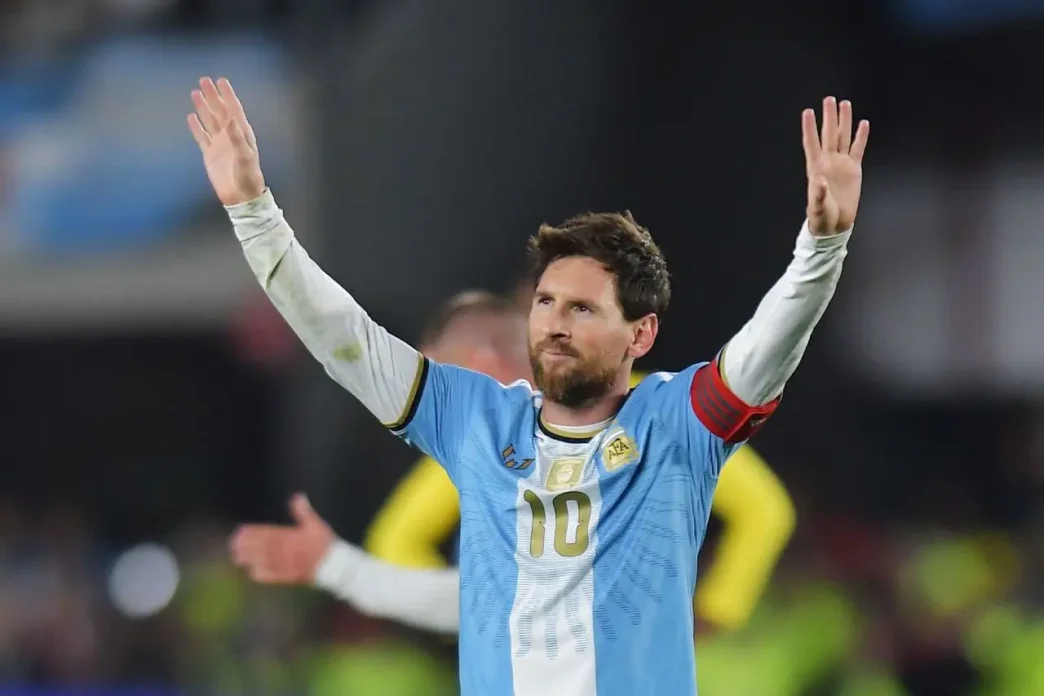 Lionel Messi saludando a la afición con los brazos en alto vistiendo la camiseta de la Selección Argentina.