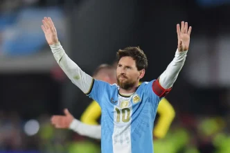Lionel Messi saludando a la afición con los brazos en alto vistiendo la camiseta de la Selección Argentina.