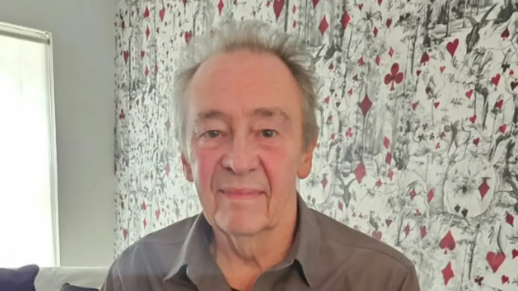 Retrato del actor y comediante británico Paul Whitehouse sonriendo frente a una pared decorada.
