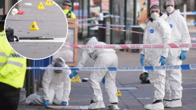 Agentes forenses vestida con trajes blancos de protección investigando la escena del tiroteo en Nottingham junto a un arma de fuego.