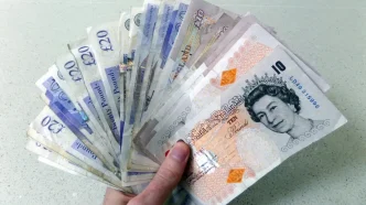 Mano sosteniendo un abanico de billetes de libras esterlinas británicas de diez y veinte libras.