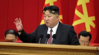 El líder norcoreano Kim Jong-un pronunciando un discurso desde un estrado con la mano levantada frente a banderas del partido.