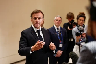 Emmanuel Macron gesticula con las manos mientras responde a periodistas con micrófonos en una comparecencia pública