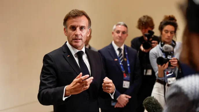 Emmanuel Macron gesticula con las manos mientras responde a periodistas con micrófonos en una comparecencia pública