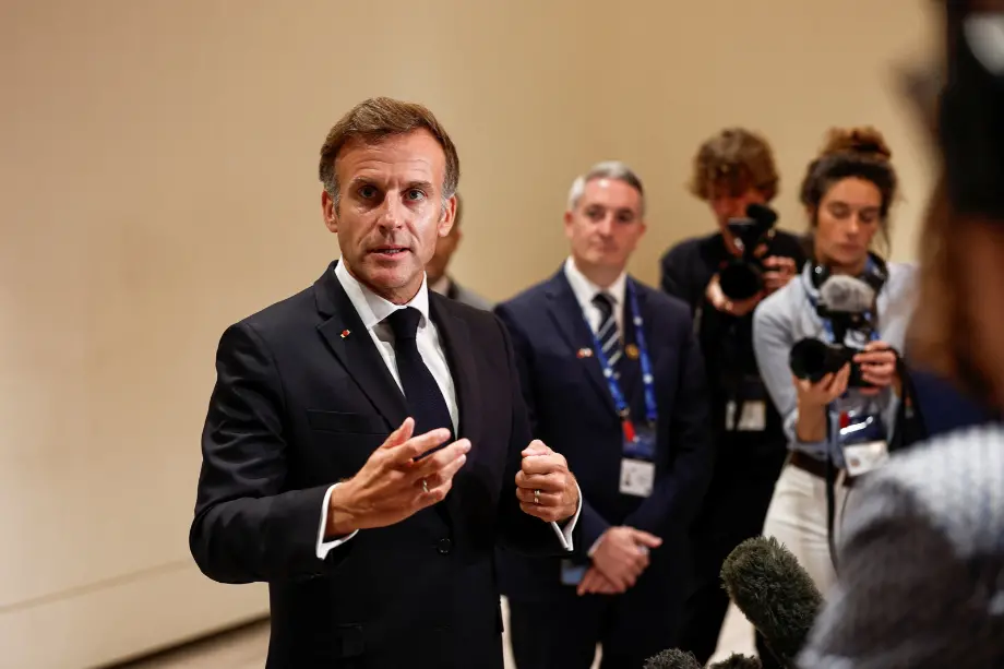 Emmanuel Macron gesticula con las manos mientras responde a periodistas con micrófonos en una comparecencia pública