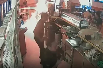 Fotograma de cámara de seguridad que muestra a un hombre rociando combustible sobre la barra de un bar en Los Palacios.