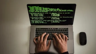 Manos de un programador escribiendo código verde sobre la pantalla de un ordenador portátil.