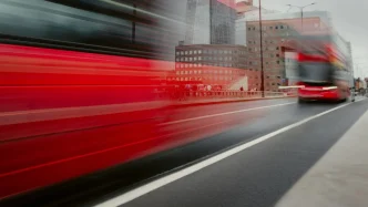 Autobús rojo de dos pisos transitando a gran velocidad por una avenida de Londres.