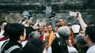 Periodistas y fotógrafos grabando con teléfonos móviles y cámaras durante una cobertura informativa en la calle.