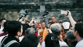 Periodistas y fotógrafos grabando con teléfonos móviles y cámaras durante una cobertura informativa en la calle.