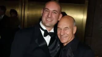El actor Sir Patrick Stewart sonriendo junto a su hijo Daniel en una gala con esmoquin.