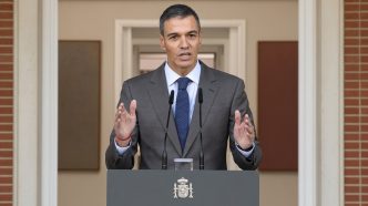 El presidente del Gobierno, Pedro Sánchez, con traje gris y corbata azul, dando una declaración institucional en el atril del Palacio de la Moncloa.