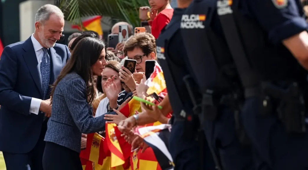 El Rey Felipe VI y la Reina Letizia saludan a la multitud con banderas de España custodiados por la Policía Nacional en Ceuta.