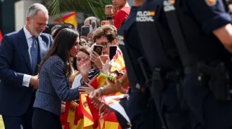 El Rey Felipe VI y la Reina Letizia saludan a la multitud con banderas de España custodiados por la Policía Nacional en Ceuta.