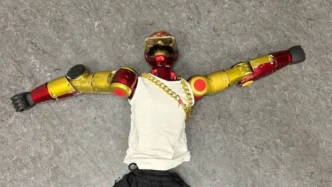 Robot humanoide rojo y dorado con camiseta blanca y bigote postizo, relacionado con una investigación policial en Alemania.