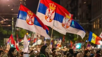 Manifestantesondeando banderas nacionales de Serbia durante una celebración política masiva en las calles de Belgrado.