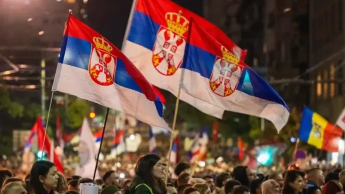 Manifestantesondeando banderas nacionales de Serbia durante una celebración política masiva en las calles de Belgrado.