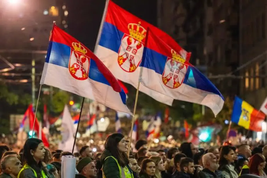Manifestantesondeando banderas nacionales de Serbia durante una celebración política masiva en las calles de Belgrado.
