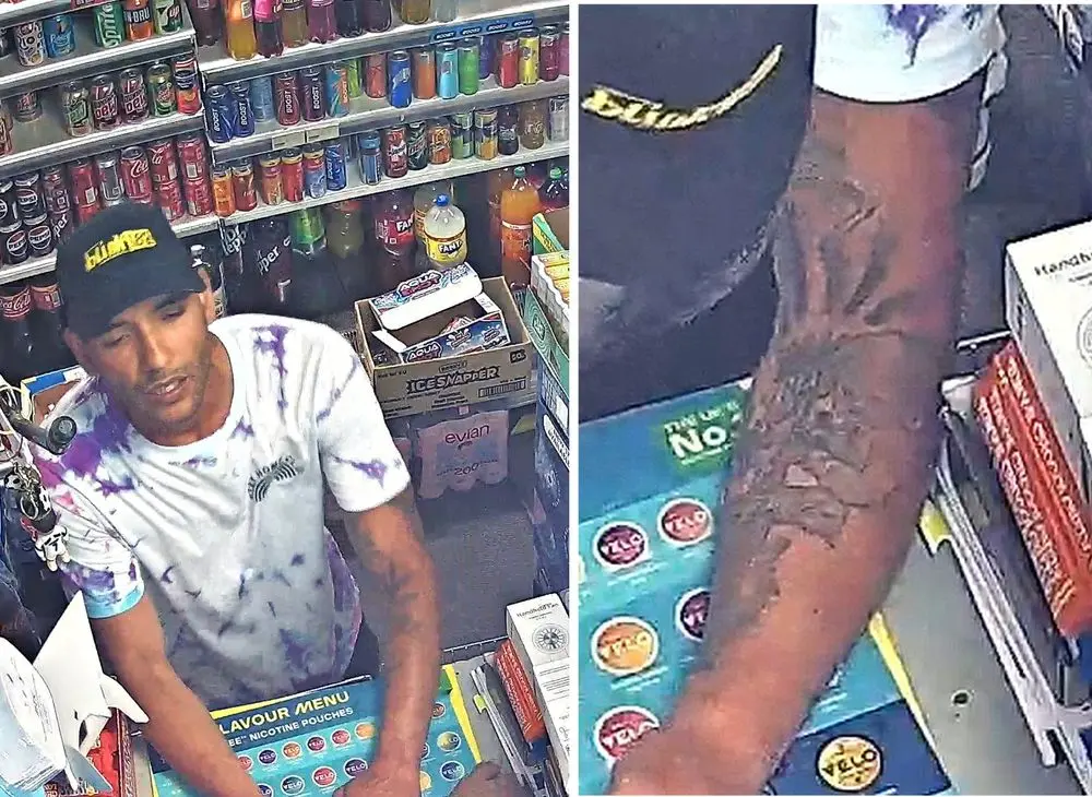 Fotografía de cámara de seguridad de un hombre con gorra negra, camiseta tie-dye azul y rosa, y tatuajes detallados en el brazo izquierdo.