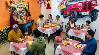 Clientes disfrutando de platos típicos colombianos en las mesas de un restaurante decorado con un jeep Willys rojo en la pared.